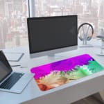 Infidu Dreamy Purple and Green Abstract Desk Pad with soft, blended colors in purple, green, and pink, featuring a smooth, dreamy design. A computer and laptop are next to the desk pad