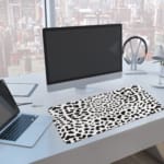 Infidu Black Leopard Print Desk Pad features a bold black leopard print pattern on a white background, offering a modern and stylish look. A computer and laptop are next to the desk pad
