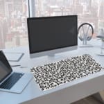 Infidu Black Leopard Print Desk Pad features a bold black leopard print pattern on a white background, offering a modern and stylish look. A computer and laptop are next to the desk pad