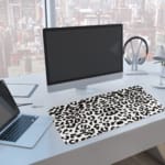 Infidu White Leopard Print Desk Pad features black spots on a white background, creating a classic and stylish leopard print design. A computer and laptop are next to the desk pad