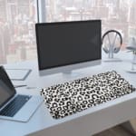 Infidu White Leopard Print Desk Pad features black spots on a white background, creating a classic and stylish leopard print design. A computer and laptop are next to the desk pad