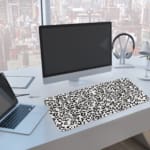 Infidu White Leopard Print Desk Pad features black spots on a white background, creating a classic and stylish leopard print design. A computer and laptop are next to the desk pad