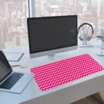 Infidu Vibrant Pink and White Striped Desk Mat with dynamic alternating pink and white stripes. A computer and laptop are next to the desk pad