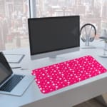 Pink and white polka dot desk pad with a classic pattern design. A computer and laptop are next to the desk pad