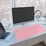 Infidu Light Pink Desk Pad with White Diamond Pattern A computer and laptop are next to the desk pad