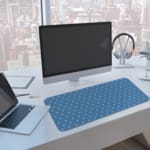 Blue and white polka dot desk pad with a classic pattern design. A computer and laptop are next to the desk pad
