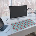 Infidu desk pad with red Christmas trees and blue teacups on a light blue background, creating a festive and cheerful design. A computer and laptop are next to the desk pad