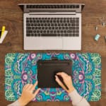 Infidu Colorful Teal and Pink Mandala Design Desk Pad with intricate teal, pink, and white patterns. A writing pad on top of the desk pad