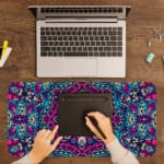 Infidu Colorful Mandala Design Desk Pad with intricate patterns in pink, blue, purple, and teal, plus white and black accents. A writing pad on top of the desk pad