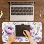 Infidu Soft Floral Desk Pad with white background, large purple and lavender flowers, and light gray and blue leaves. A writing pad on top of the desk pad