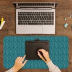 Desk pad with a green background and white ripple design, resembling water-like waves. A writing pad on top of the desk pad