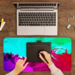 Infidu Vibrant Green and Pink Gradient Desk Pad with wave-like patterns in green, pink, and purple A writing pad on top of the desk pad