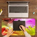 Infidu Colorful Abstract Wavy Lines Desk Pad featuring vibrant, flowing lines in pink, purple, yellow, orange, and green. A writing pad on top of the desk pad