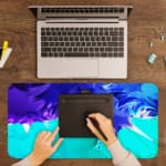 Infidu Abstract Desk Pad with blue, purple, and green colors, featuring sharp and flowing lines on a light background. A writing pad on top of the desk pad