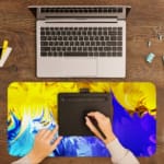 Infidu Abstract Desk Pad with yellow, blue, and green colors in flowing patterns on a vibrant background. A writing pad on top of the desk pad