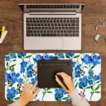 Blue floral desk pad with green leaves on a white background. A writing pad on top of the desk pad
