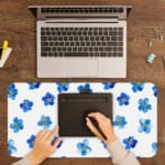 Desk pad with blue flowers evenly spaced on a white background. A writing pad on top of the desk pad