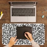 Infidu Black Leopard Print Desk Pad features a bold black leopard print pattern on a white background, offering a modern and stylish look. A writing pad on top of the desk pad