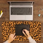 Infidu Leopard Print Design Desk Pad with black spots on a yellow background, simulating a leopard's natural fur. A writing pad on top of the desk pad