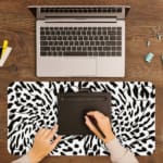 Infidu Bold Black and White Abstract Print Desk Pad with black abstract shapes on a white background, resembling animal print. A writing pad on top of the desk pad