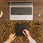 Infidu Leopard Print Desk Pad features a leopard print pattern with a brown background and black spots, resembling natural leopard fur. A writing pad on top of the desk pad