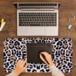 Infidu White Desk Pad with Bold Leopard Print Design featuring black and brown spots on a white background. A writing pad on top of the desk pad