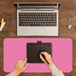 Pink diagonal striped desk pad with a soft and pastel design, featuring thin pink stripes on a light background. A writing pad on top of the desk pad