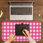 Pink and white checkered desk pad with a grid-like pattern on a white background. A writing pad on top of the desk pad