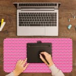 Pink desk pad with a pattern of small, evenly spaced triangles. A writing pad on top of the desk pad