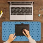Desk pad featuring small black polka dots on a blue background. A writing pad on top of the desk pad