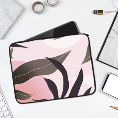 Laptop sleeve with abstract dark gray and black leaves on a soft pink background, offering a modern and elegant design. laptop sleeve kept on a plain white background