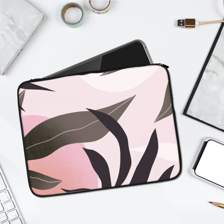 Laptop sleeve with abstract dark gray and black leaves on a soft pink background, offering a modern and elegant design. laptop sleeve kept on a plain white background
