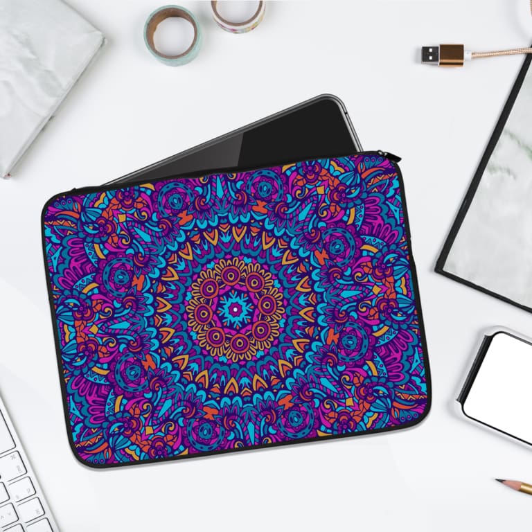 A colorful laptop sleeve with a mandala-like design in vibrant shades of pink, blue, and green, featuring a secure zip for protection. laptop sleeve kept on a plain white background