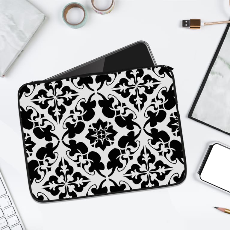 Laptop sleeve with black and white vintage tile pattern, featuring an elegant, symmetrical design and secure zip closure. laptop sleeve kept on a plain white background