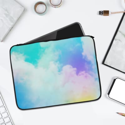 Infidu Cloud Pastel Sky Dreamy Laptop Sleeve with soft pastel colors transitioning between blue, yellow, pink, and purple. the laptop sleeve on the table