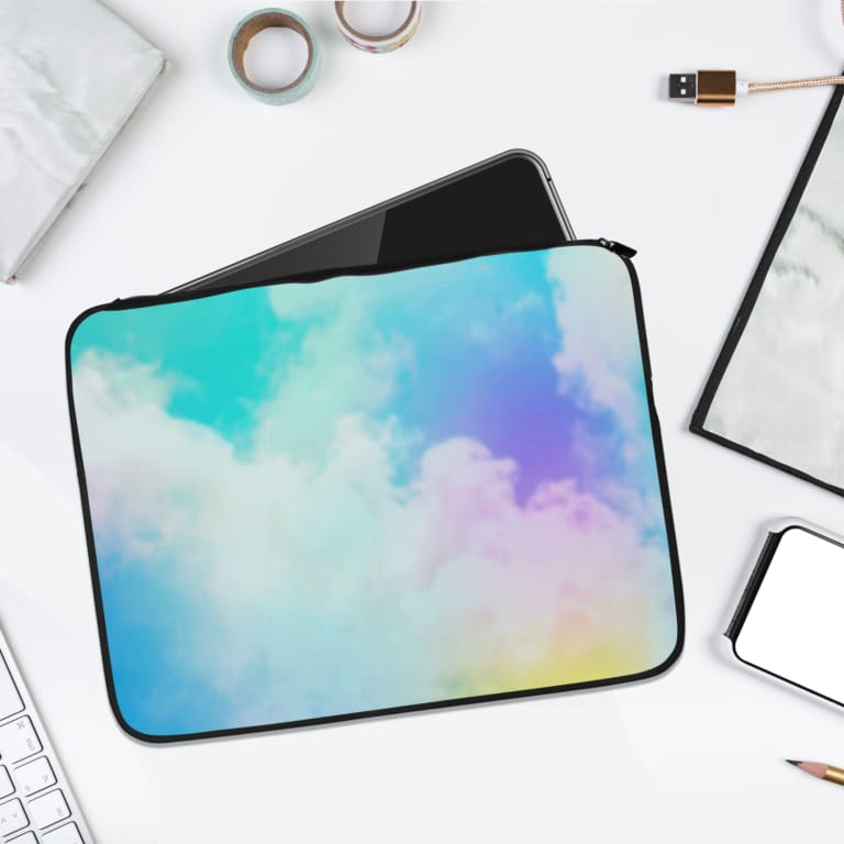 Infidu Cloud Pastel Sky Dreamy Laptop Sleeve with soft pastel colors transitioning between blue, yellow, pink, and purple. the laptop sleeve on the table