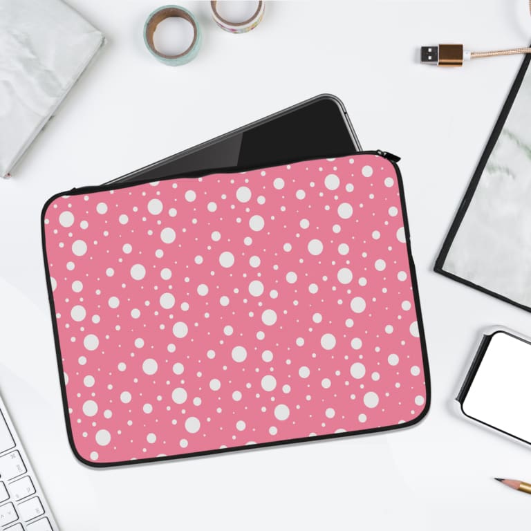 Pink and white polka dot patterned laptop sleeve with durable fabric and secure zip closure, ideal for stylish and practical laptop protection. laptop sleeve kept on a plain white background