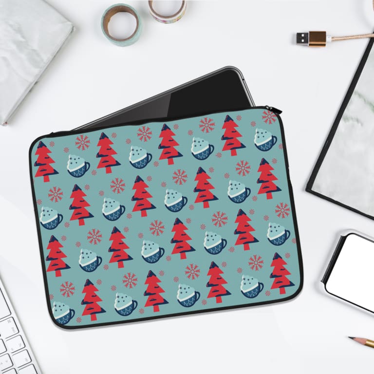Festive Christmas Tree & Snowflake Laptop Sleeve with red Christmas trees and light blue snowflakes on a blue-green background. laptop sleeve kept on a plain white background
