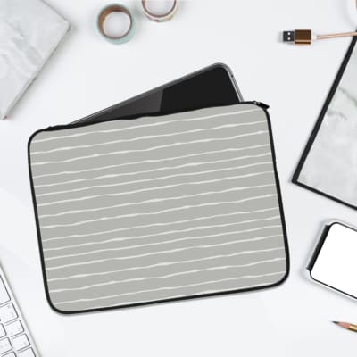 Minimalist gray laptop sleeve with thin white horizontal stripes, featuring a durable fabric and zip closure for secure laptop protection. laptop sleeve kept on a plain white background