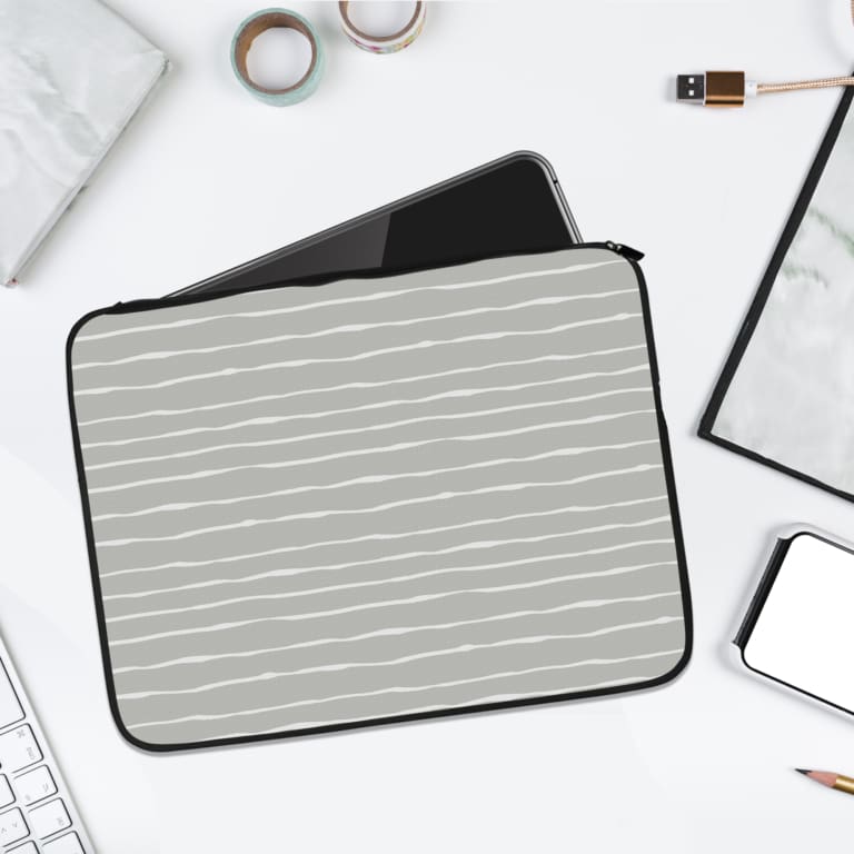 Minimalist gray laptop sleeve with thin white horizontal stripes, featuring a durable fabric and zip closure for secure laptop protection. laptop sleeve kept on a plain white background