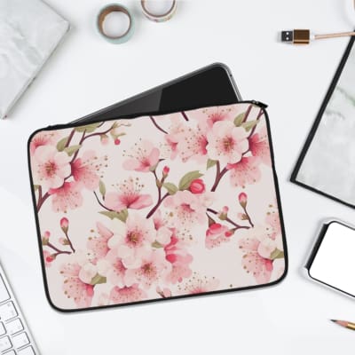 White laptop sleeve with soft pink blossoms and brown branches, featuring a secure zip closure for protection and style. laptop sleeve kept on a plain white background