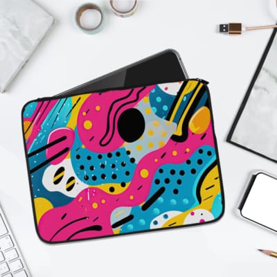 Abstract colorful laptop sleeve featuring pink, yellow, blue, and black wavy shapes and polka dots for a modern and vibrant look. laptop sleeve kept on a plain white background