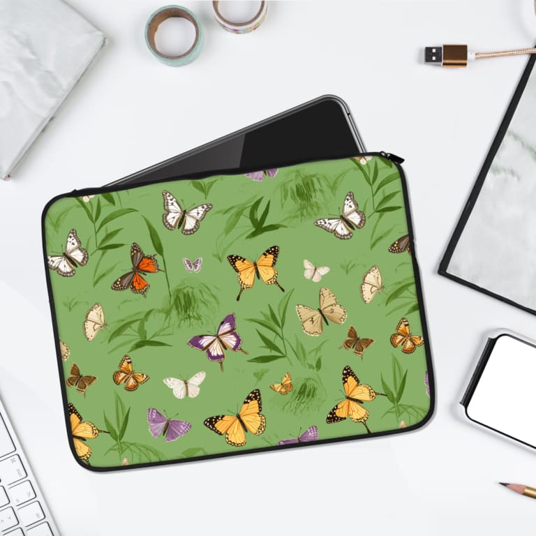 Nature-inspired laptop sleeve with colorful butterflies and grass design on a green background. laptop sleeve kept on a plain white background