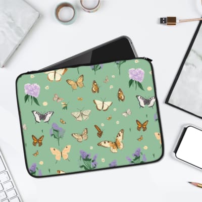 Nature-inspired laptop sleeve featuring colorful butterflies, purple flowers, and a green background. laptop sleeve kept on a plain white background