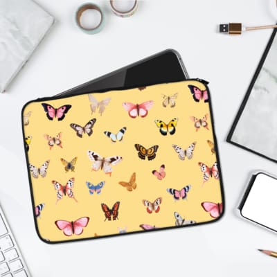 Sandal-colored laptop sleeve with pink, yellow, and blue butterfly designs, offering minimalist and elegant style for everyday use. laptop sleeve kept on a plain white background