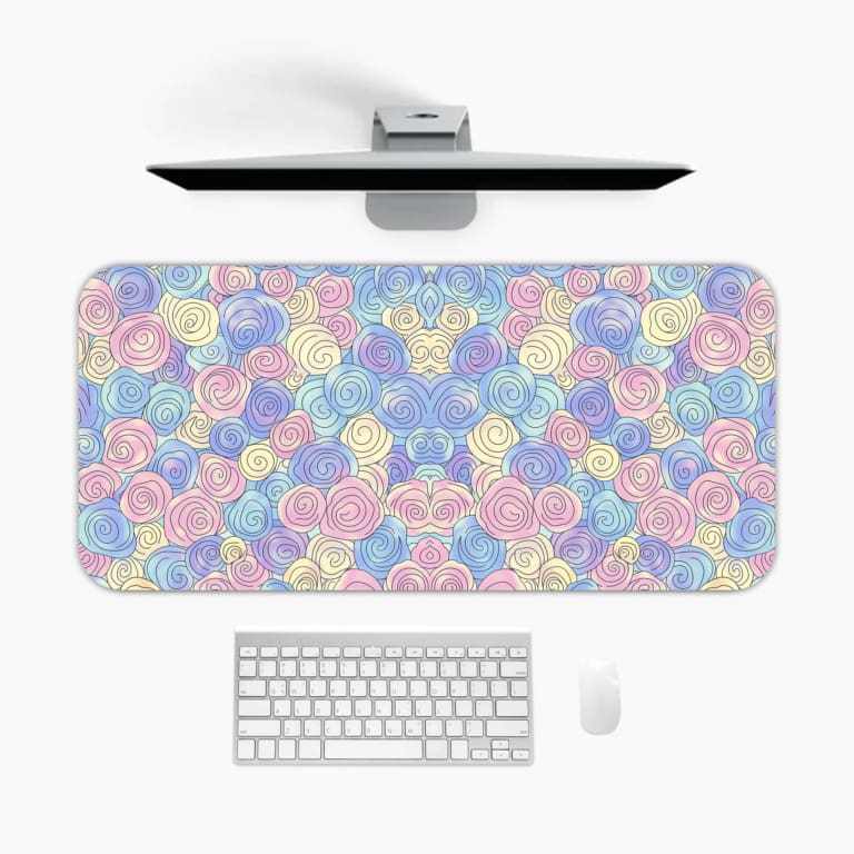 Infidu desk pad featuring colorful pastel abstract design with pink, blue, and purple patterns against a light blue background. A desk pad under the computer