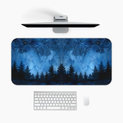 Infidu desk pad featuring a dark starry night forest design with deep blue tones and pine tree silhouettes against a starlit sky. A desk pad under the computer