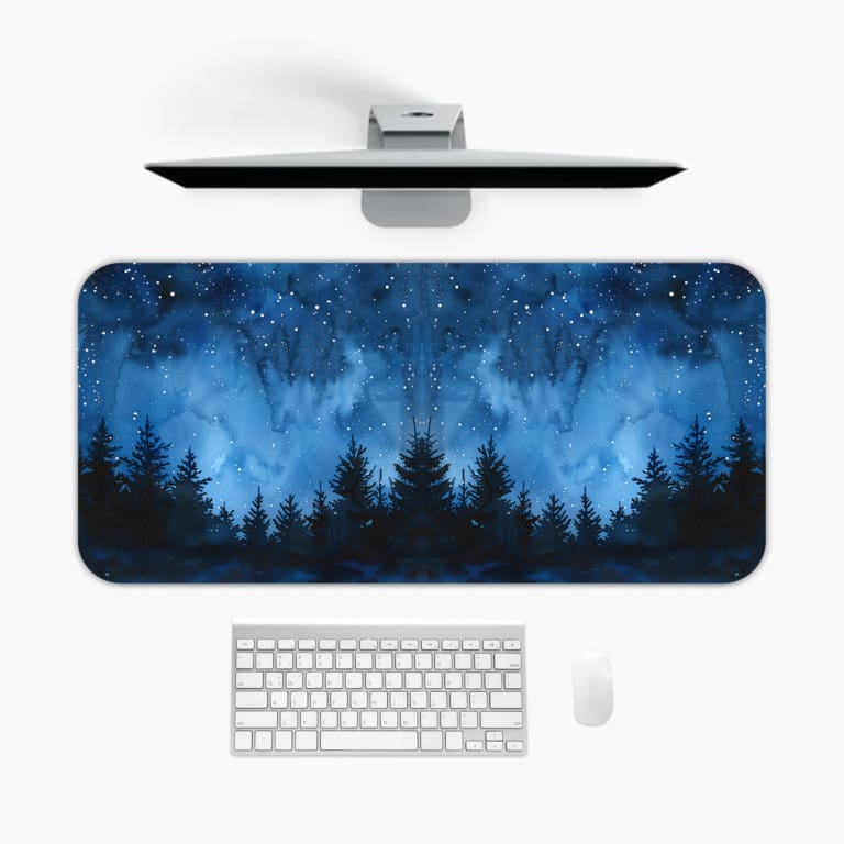 Infidu desk pad featuring a dark starry night forest design with deep blue tones and pine tree silhouettes against a starlit sky. A desk pad under the computer