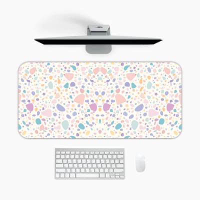 Infidu desk pad with terrazzo-style pattern in pastel colors on a light background, featuring small scattered shapes for a subtle modern look. A desk pad under the computer