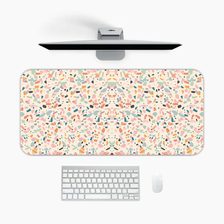 Infidu desk pad with a playful confetti pattern featuring small, colorful shapes on a light background. A desk pad under the computer
